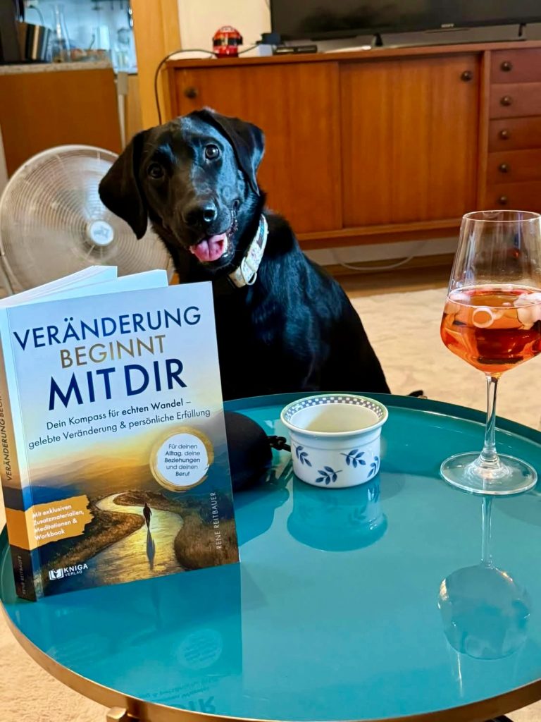Buch „Veränderung beginnt mit dir“ auf einem Tisch neben einem Hund